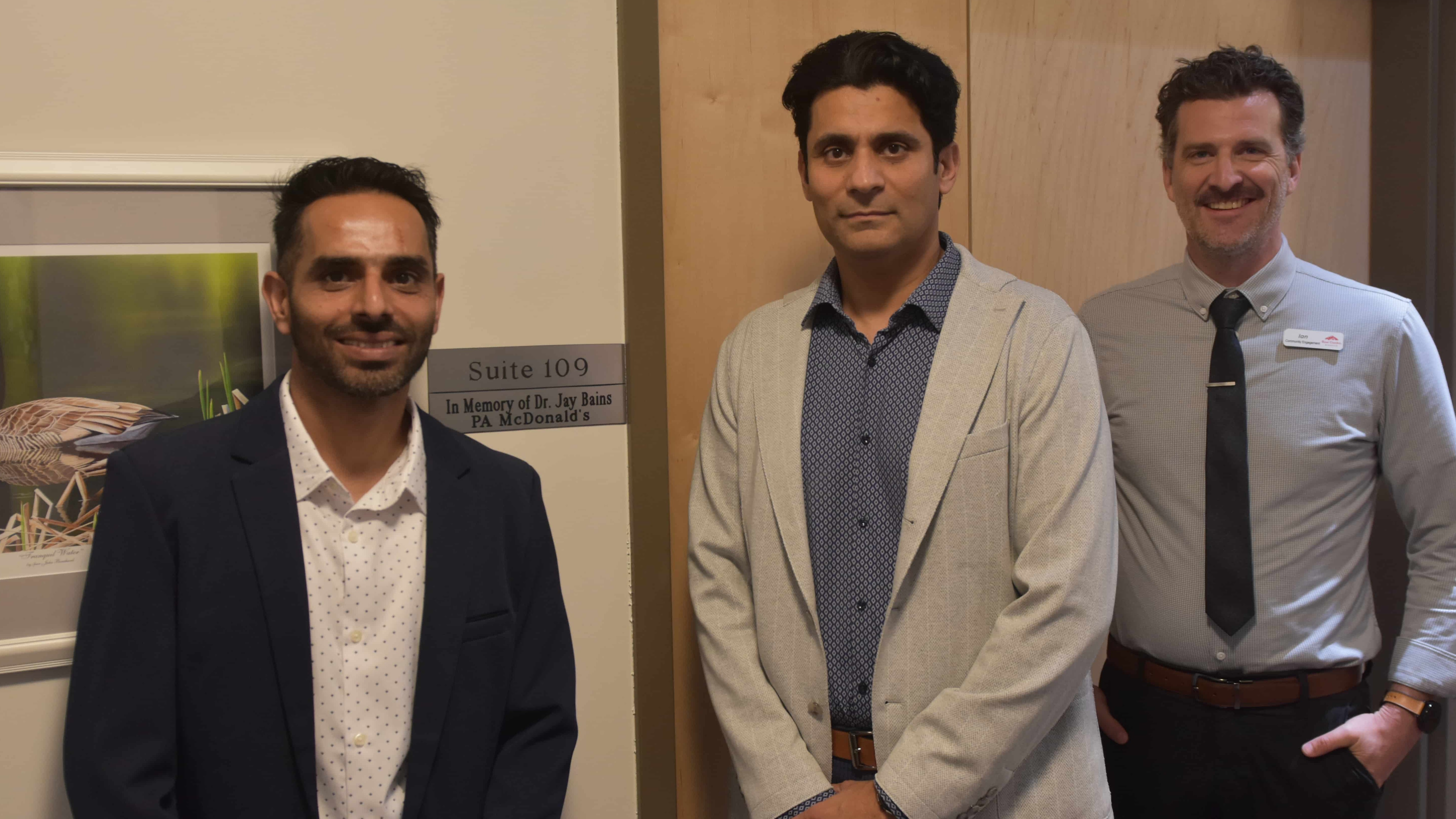 Raj Bains (middle) stands with Gaurav Kumar (right), McDonald's Prince Albert's operational manager, and Ian Dickson in front of Suite 109 at the Rose Garden Hospice in PA, proudly displaying a new name in honour of Bains' father.