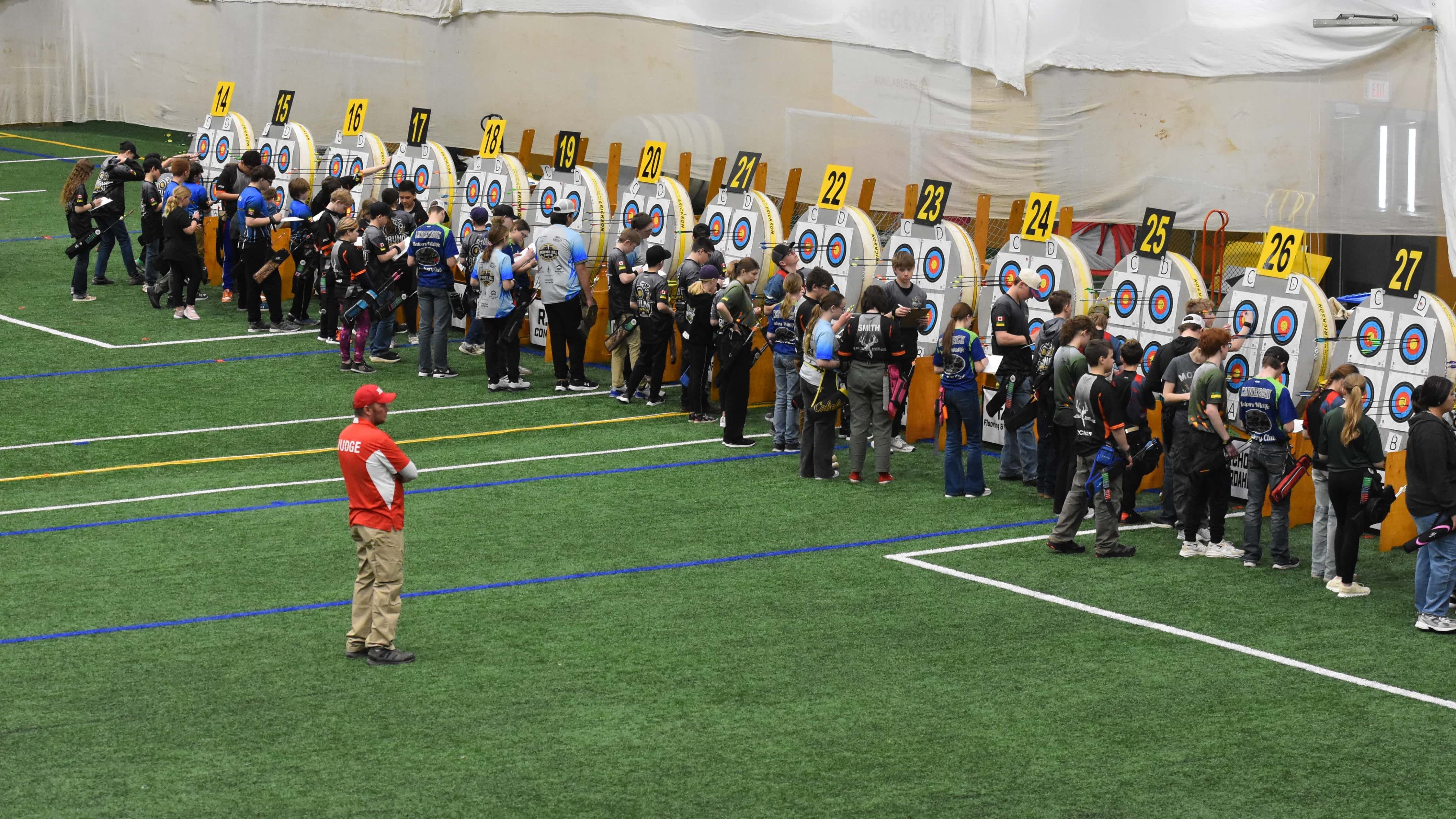 A judge observes the competitors as they tally their scores.
