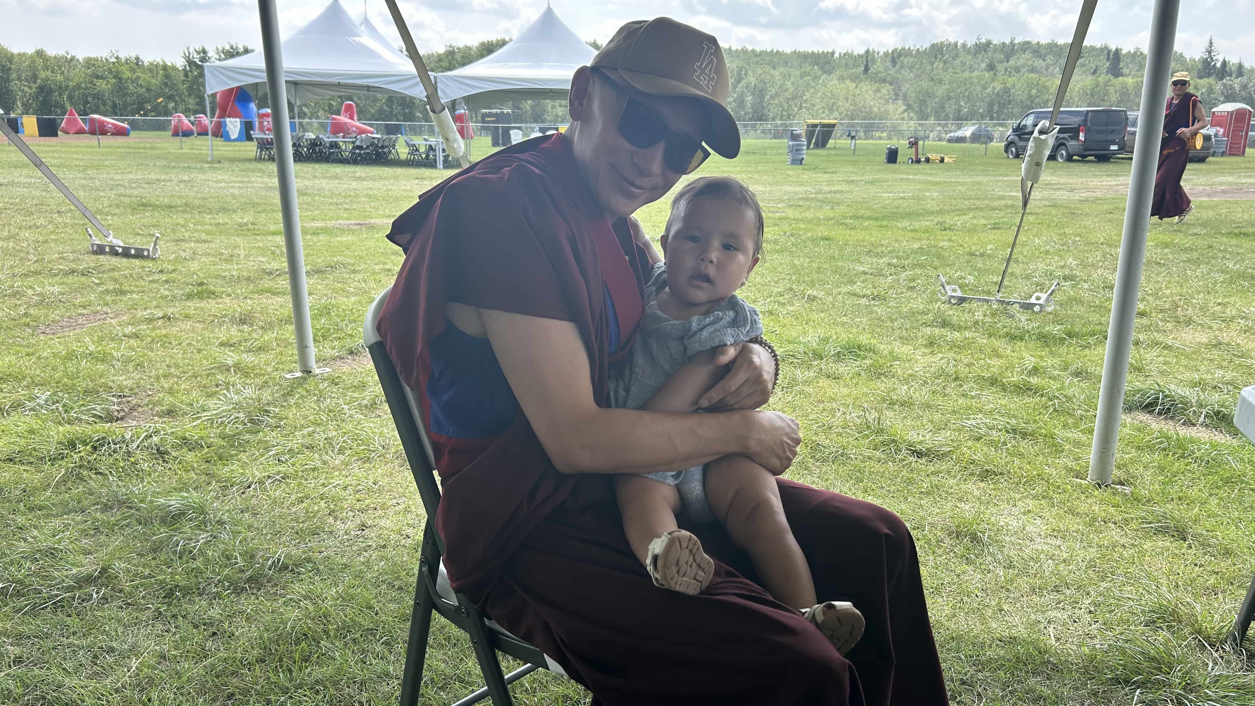 A child from Ahtahkakoop Cree Nation sits on the lap of one of the monks during Ahtahkakoop's Family Day celebrations.