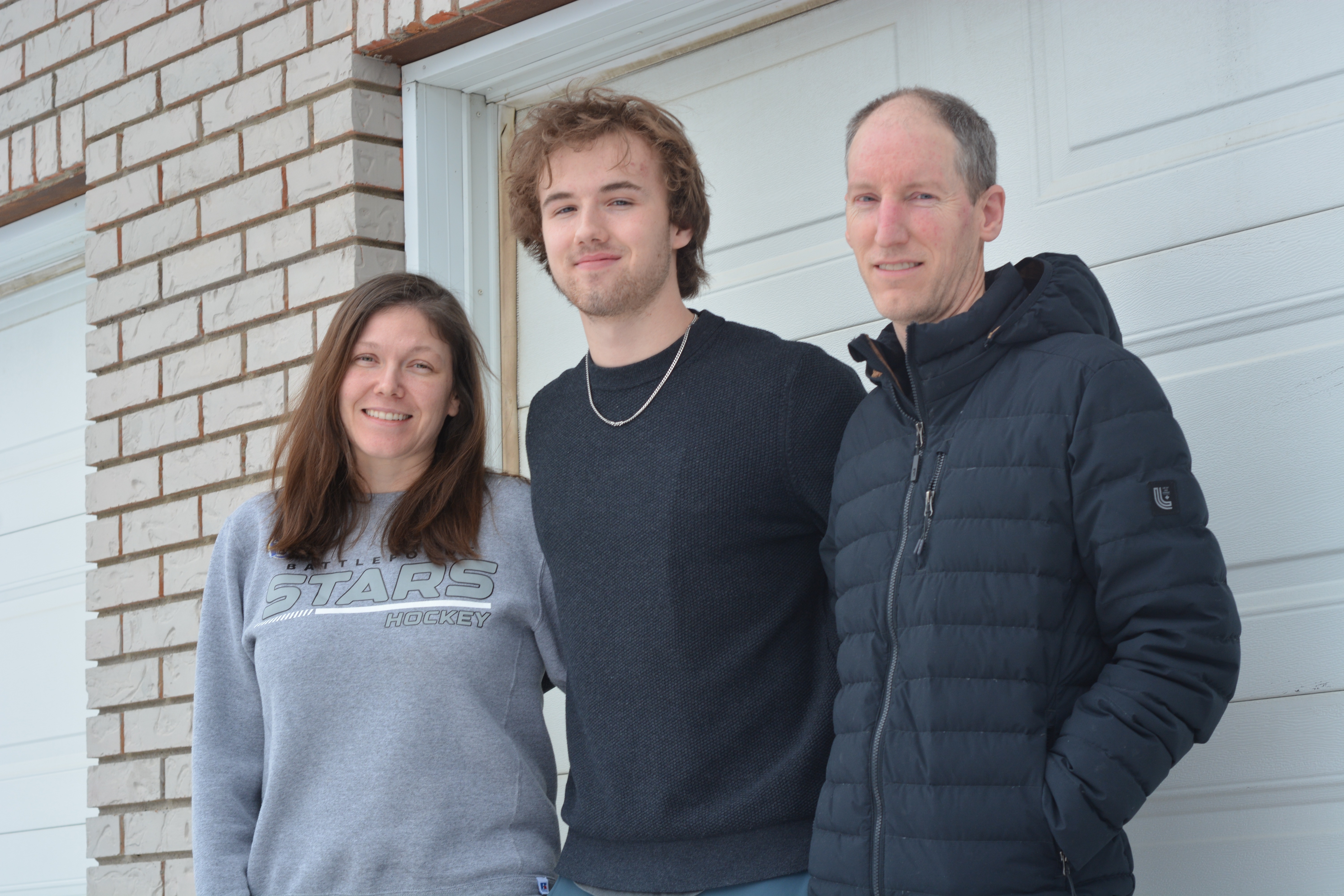 From left, Kendra Nelson, Finlay Klippenstein and Craig Nelson pose outside the Nelson family’s home in North Battleford.