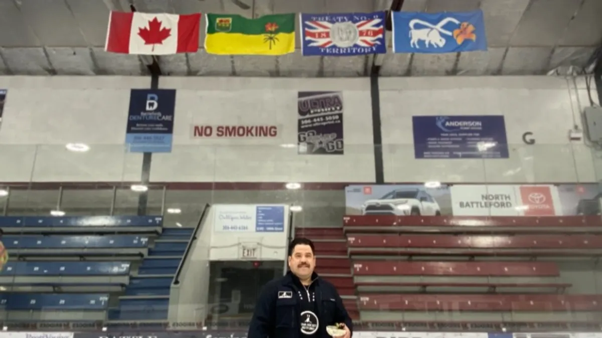 Tyson Wuttunee standing in front of the flags.